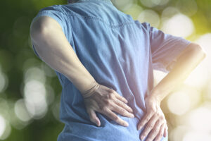 Woman wearing denim blue shirt touching her painful lower back