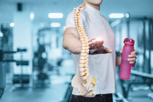 Male athlete holding a water bottle and pointing to a model of the spine