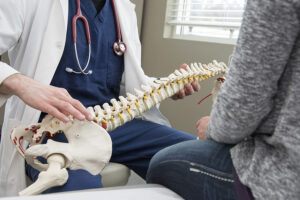 Orthopedic spine surgeon holding model spine and talking with patient