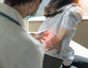 Orthopedic spine surgeon examining a female patient's painful lower back