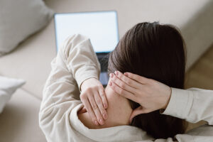 Woman sitting in front of computer rubbing the back of her sore neck