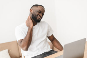 Man with neck pain sitting in front of laptop computer
