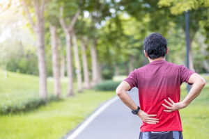 Young male runner pausing on a running path due to low back pain