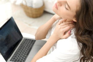 Woman paused while working at computer to massage her painful neck