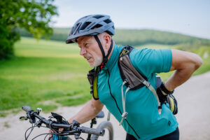 Active senior man experiencing low back pain after cycling on country road